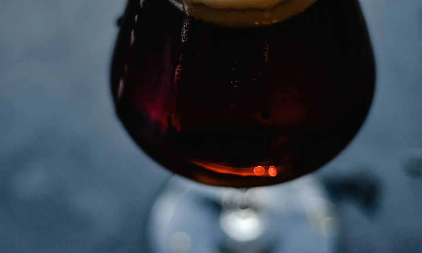 Dark ale with a soft frothy head against a charcoal background.