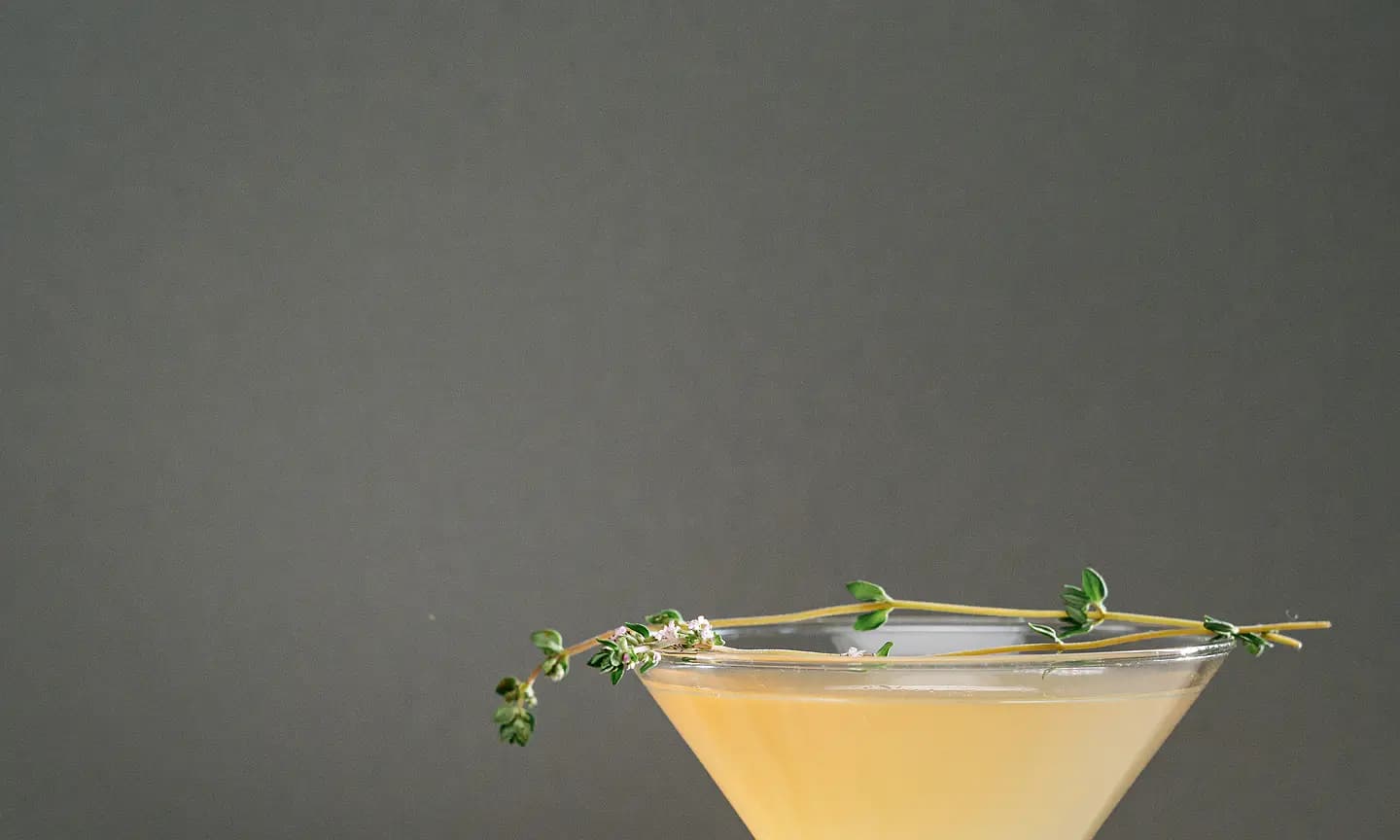 Pale botanical cocktail with a restrained herb garnish.