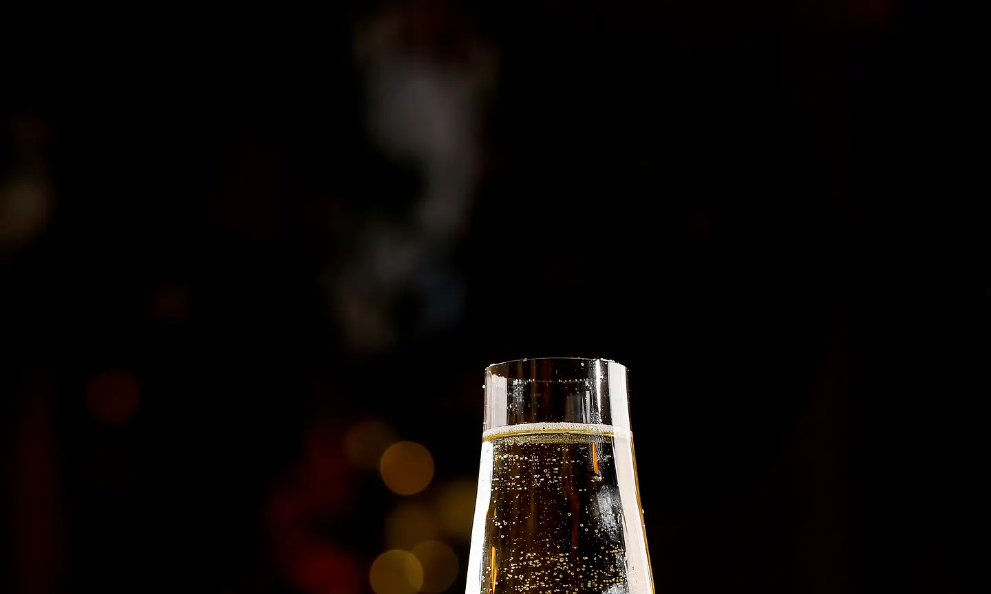 Sparkling wine in a stemmed glass with warm evening bokeh.