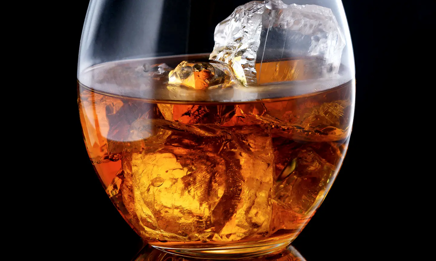 Amber spirit served over ice in a rocks glass.