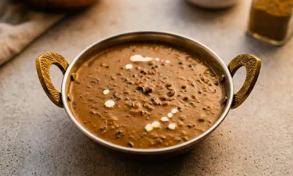 Dal Makhani served in a handled metal bowl.