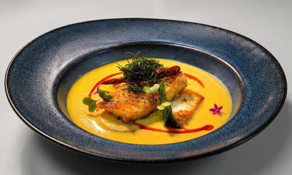 Fish Moilee served in a dark blue-gray bowl.