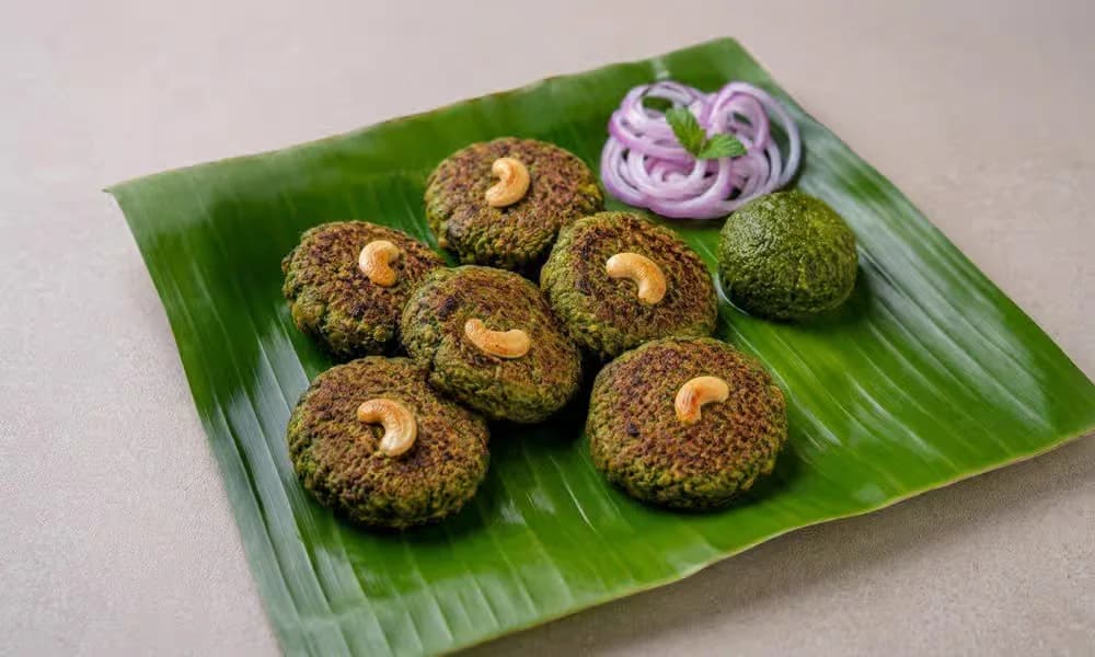 Hara Bhara Kebab arranged on a banana leaf with onion and chutney.