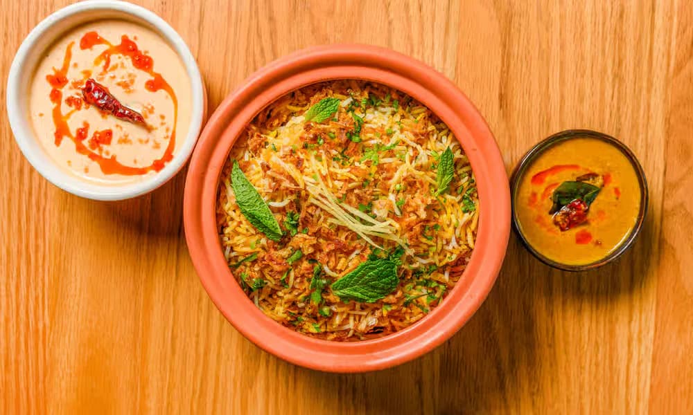 Hyderabadi Chicken Dum Biryani served with raita and gravy.