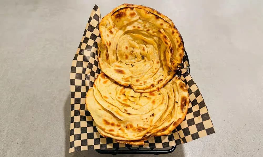 Lachcha Paratha stacked in a lined bread basket.