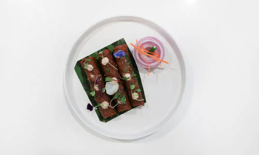Lamb Seekh Kebab presented with onion and chutney.