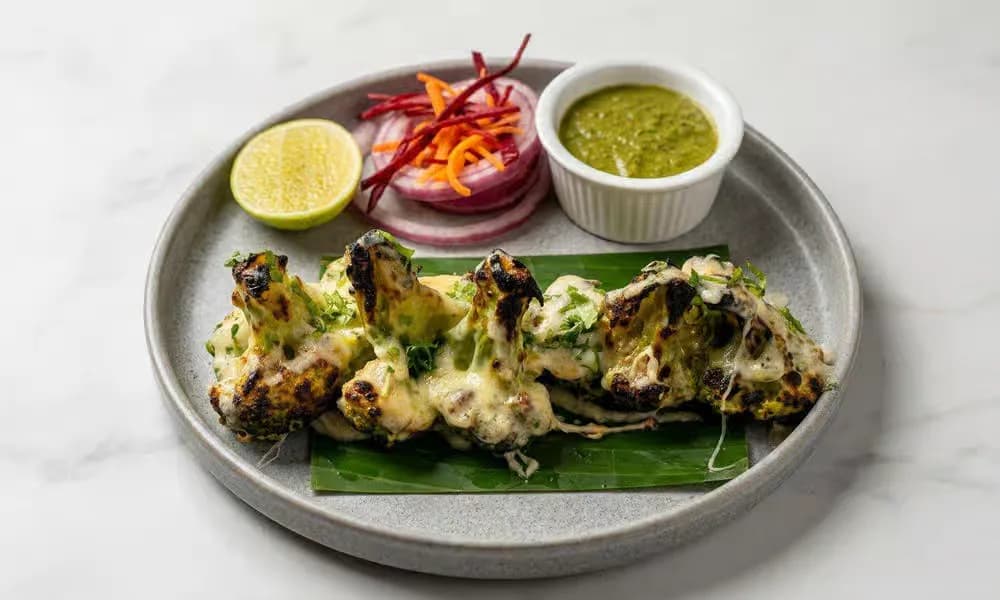 Malai Tandoori Broccoli served with onion, lemon, and green chutney.