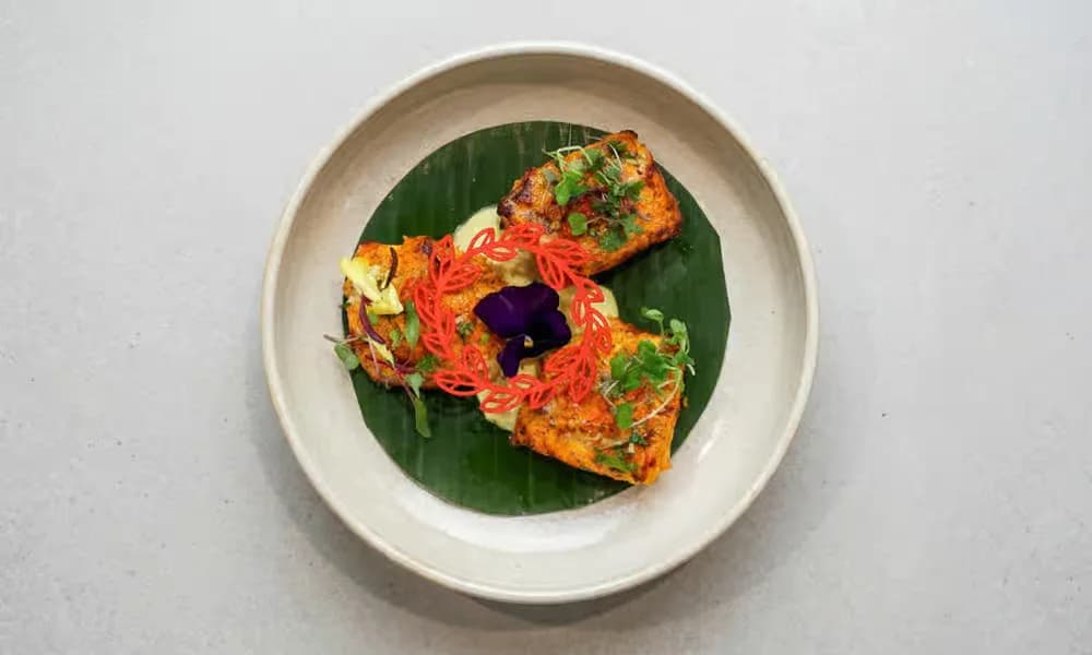 Tandoori Salmon plated with greens and edible flowers.