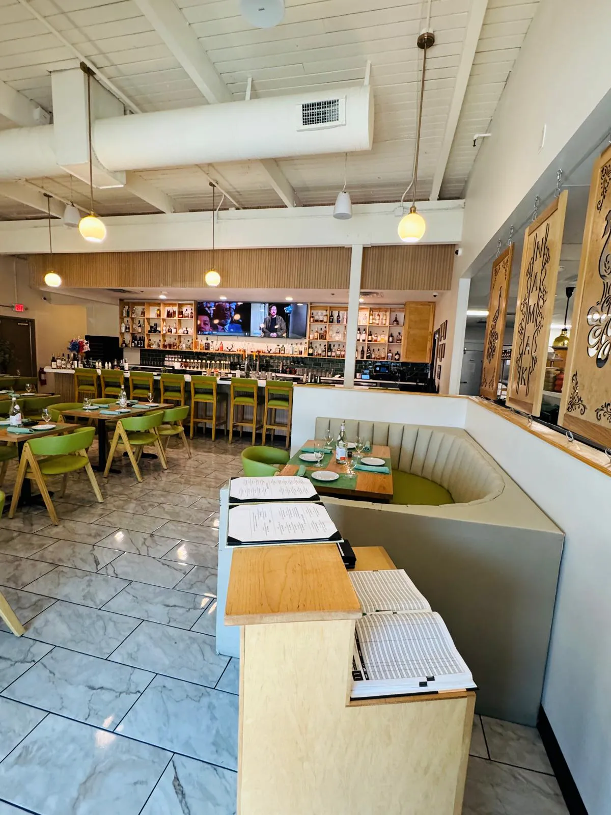 Architectural view through the Namak dining room with booth seating and pendant lights.