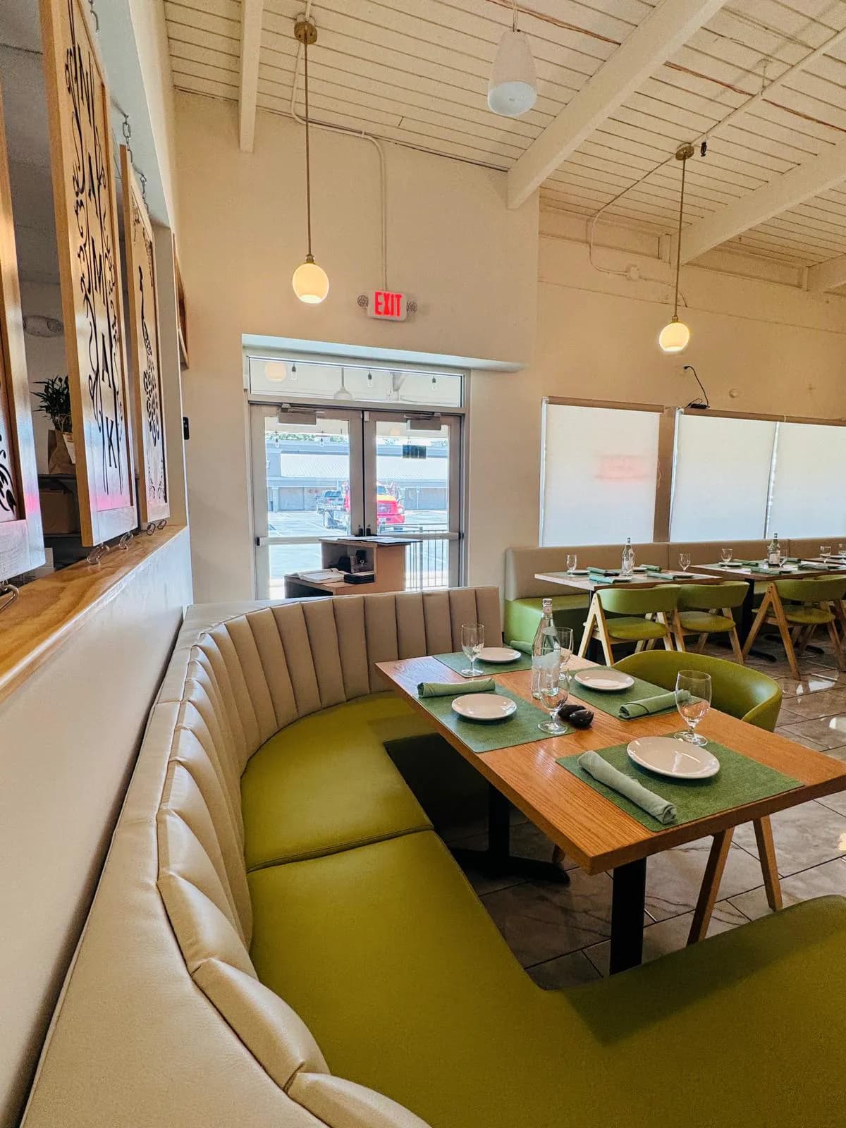 Curved upholstered booth and set dining table near the Namak entrance.