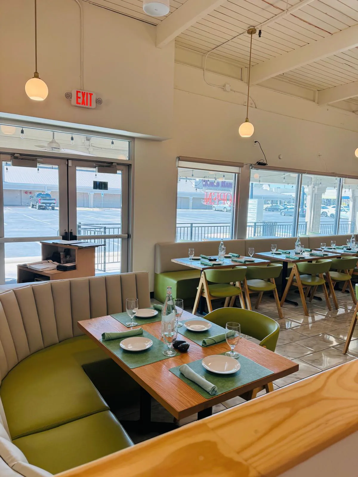 Curved booth and green chairs around a set table in the Namak dining room.